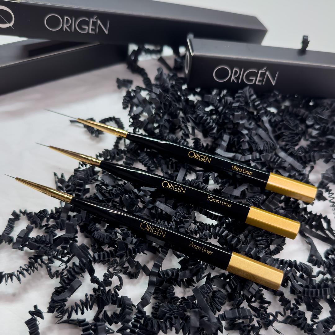 Origen liner brushes with branded cases in the background.